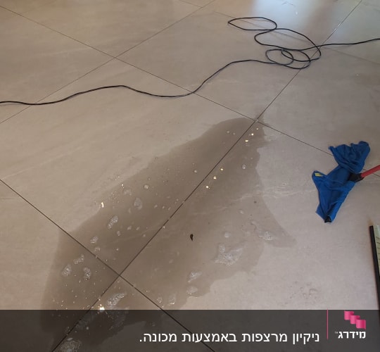 מגב כחול על רצפה רטובה עם שלולית מים